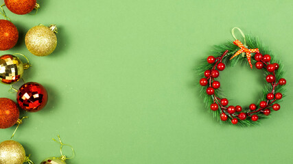 Christmas background with balls and Christmas wreath on green background. Text space, top view