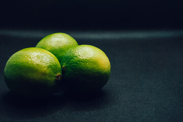 Three green limes on black background. Shallow depth of focus, blur, fruit, 3, trio.