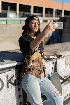 Mujer joven adolescente con skate monopatín en skatepark haciendo fotos selfies