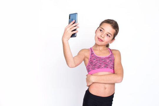 Pretty young sport and healthy girl in fitness dress makes selfie with mobile phone. Isolated photo on white background with copy space.