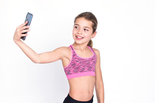 Beautiful slim young sport and healthy girl in sportswear makes selfie with cellphone. Isolated photo on white background with copy space.