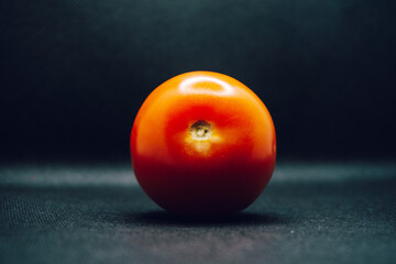 Single tomato on black background. Vegetable, shiny, studio, shallow focus, blur, one, 1, individual, dark, lighting, contrast.