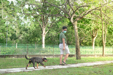 Man wearing face mask walking with dog at the park