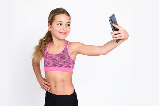 Beautiful young sport and healthy girl in fitness dress makes selfie with mobile phone. Isolated photo on white background with copy space.