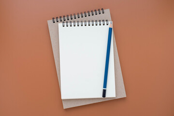 Top view above of open blank spiral notebook and pencil isolated on brown background for design a mockup. Education and business concept. flat lay