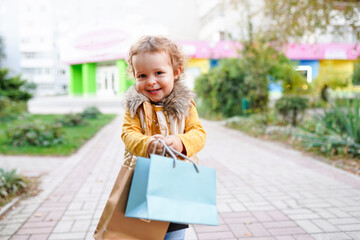 Beautiful little girl holding shopping colorful paper bags