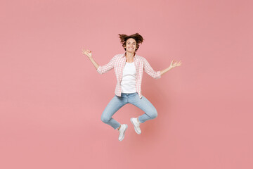 Full length of smiling young woman 20s in casual checkered shirt jumping hold hands in yoga gesture relaxing meditating, trying to calm down isolated on pastel pink colour background, studio portrait.