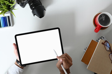 Top view of young professional designer drawing his project with blank screen tablet in comfortable workspace.