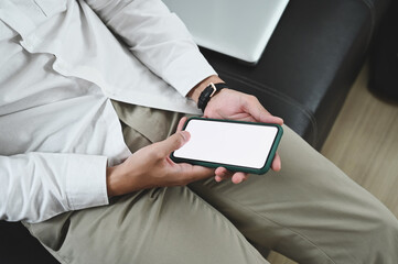 Close up view of businessman holding his smartphone for relax while sitting in his office room.