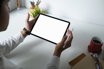 Cropped shot of male designer using empty screen digital tablet with stylus pen on white office...