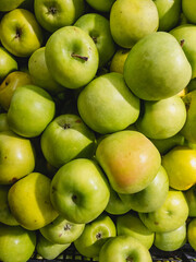 Ripe green apples are on top of each other in a hypermarket for sale.