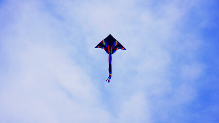 A blue flying kite. Colrful kite flying in the blue clear sky.