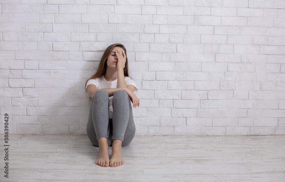 Wall mural Lonely young woman sitting on floor at home, feeling depressed and hopeless, copy space - Wall murals
