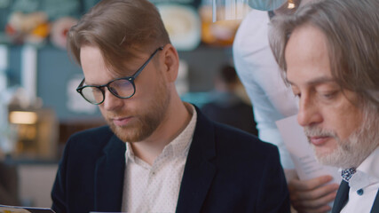 Business people reading menu and ordering in restaurant