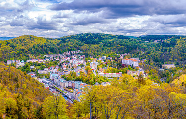 Fototapeta na wymiar Karlovy Vary city aerial panoramic view with row of colorful multicolored buildings and spa hotels in historical city centre. Panorama of Karlsbad town and Slavkov Forest mountains in autumn