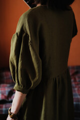 Woman in olive linen puff sleeve dress indoors. Natural fabric clothes concept.