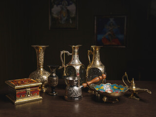 Indian bronze vases and tableware on wooden table 