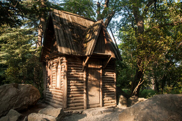 A small wooden hut with carved frames among the rocks in the forest. Fairytale house.