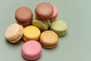 Colored tasty macaroons over a green background.