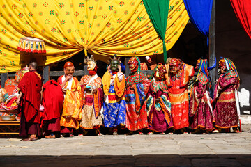Naklejka premium Bhutan, in the village of Bumthang, superior monks in colourful costumes and masks sitting during the yearly festival of Jakar. 