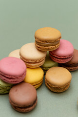Colored tasty macaroons over a green background.