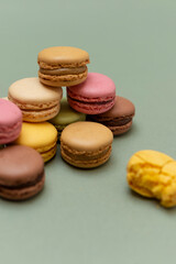Colored tasty macaroons over a green background.
