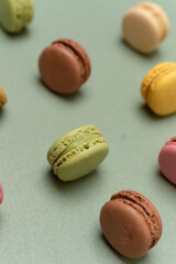 Colored tasty macaroons over a green background.