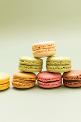 Colored tasty macaroons over a green background.