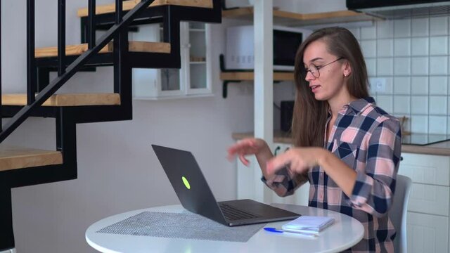 Happy young woman learning and communicates in sign language online at a computer at home