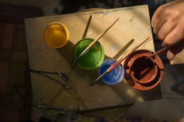 Artigiano decora a mano una piastrella di ceramica nella sua bottega