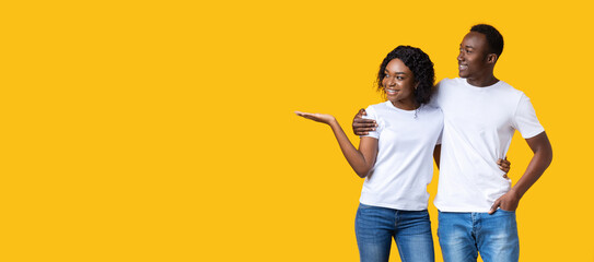 African-american man and woman showing empty space on yellow