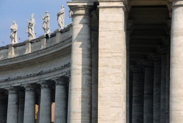 The famous colonnade of St. Peter's Square with statues in the Vatican state that is formed by large columns of travertine in a circular shape.