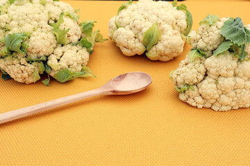 Broccoli on a yellow background with a wooden spoon, close-up, side view