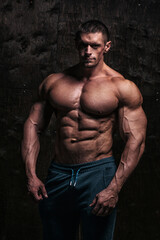 Sporty and healthy muscular man on dark grunge background - 386397069