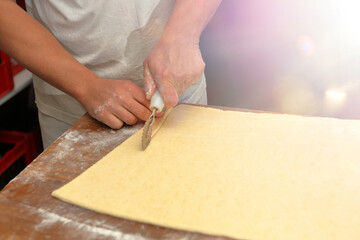 Baker cuts the dough for croissants and empty space for text