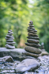 Fototapeta premium Relaxed view of a pyramid of stones balanced on a river water