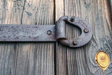 Metal door hinge with torn nails, on an old wooden gate
