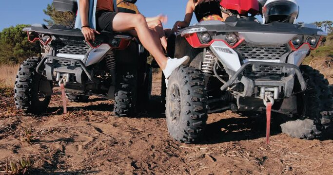 Low mid-section of friends sitting on quad bikes having fun