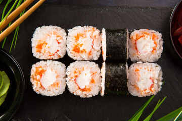 Set of sushi rolls with wasabi and ginger on black background. Japanese oriental cuisine