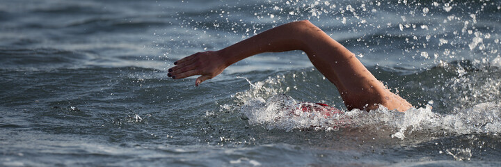 Arm of a swimmer athlete swimming in the ocean, competition swimming at triathlon