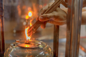 Close up hand cense joss stick with Oil lamp fire. With film grain effect