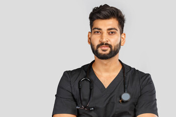 smiling indian doctor or surgeon in black uniform with stethoscope on gray background
