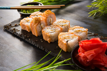 Set of baked sushi rolls with wasabi and ginger on black