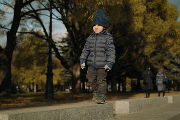 Cute little Caucasian three year old boy walking along the fountain in autumn park.