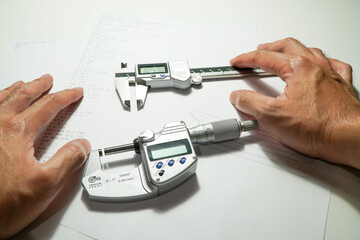 Technicians with digital micrometers and digital vernier calipers perform grading block calibrations.
