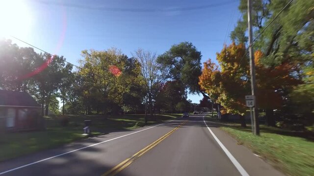 A forward driving view on typical Ohio country roads. Colorful Autumn foliage on the trees.  	