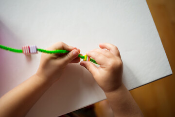 child stringing beads on string. development of baby's fine motor skills. learning in kindergarten