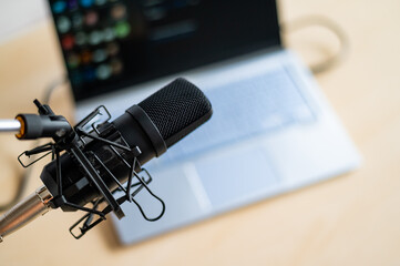 Close-up of a professional microphone on the background of a laptop. Radio broadcaster's desktop