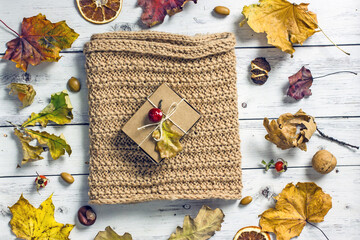 Autumn background composition flat lay with fruits, knitted scarf, acorns, fallen leaves and cones
