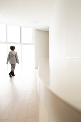Young boy walking and discovering a wide shiny white space, sun light coming through the windows